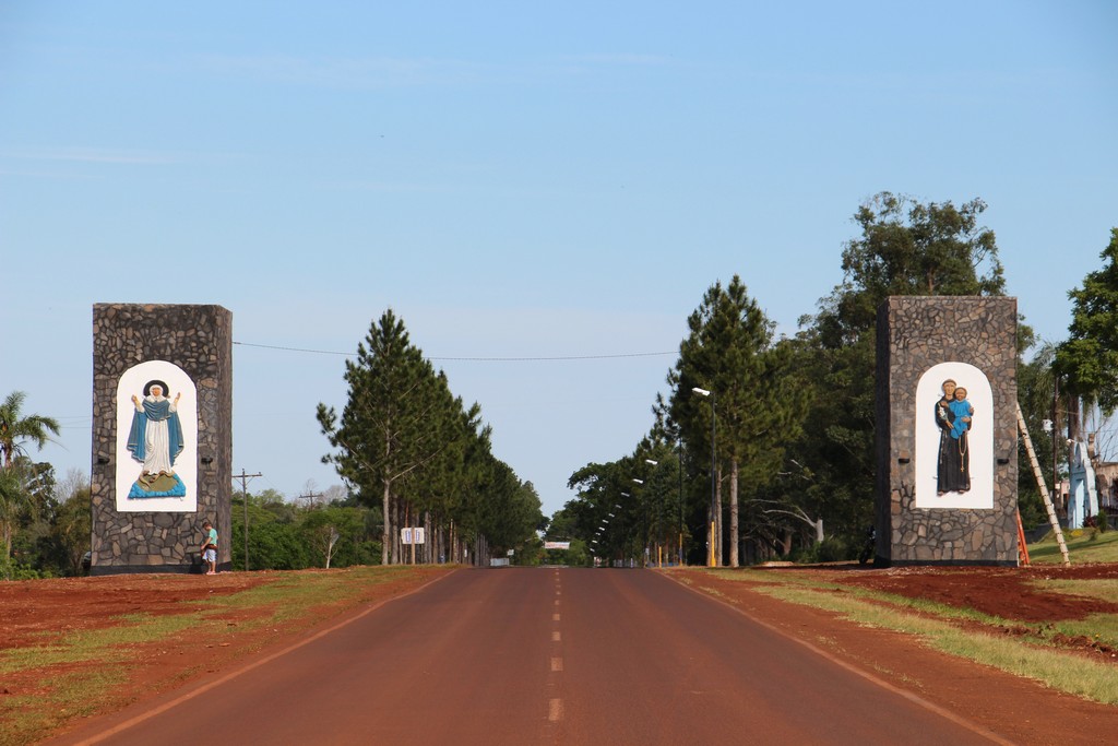 Entrada a Azara, Misiones, con dos pilares junto a la calzada y tierra colorada en las banquinas
